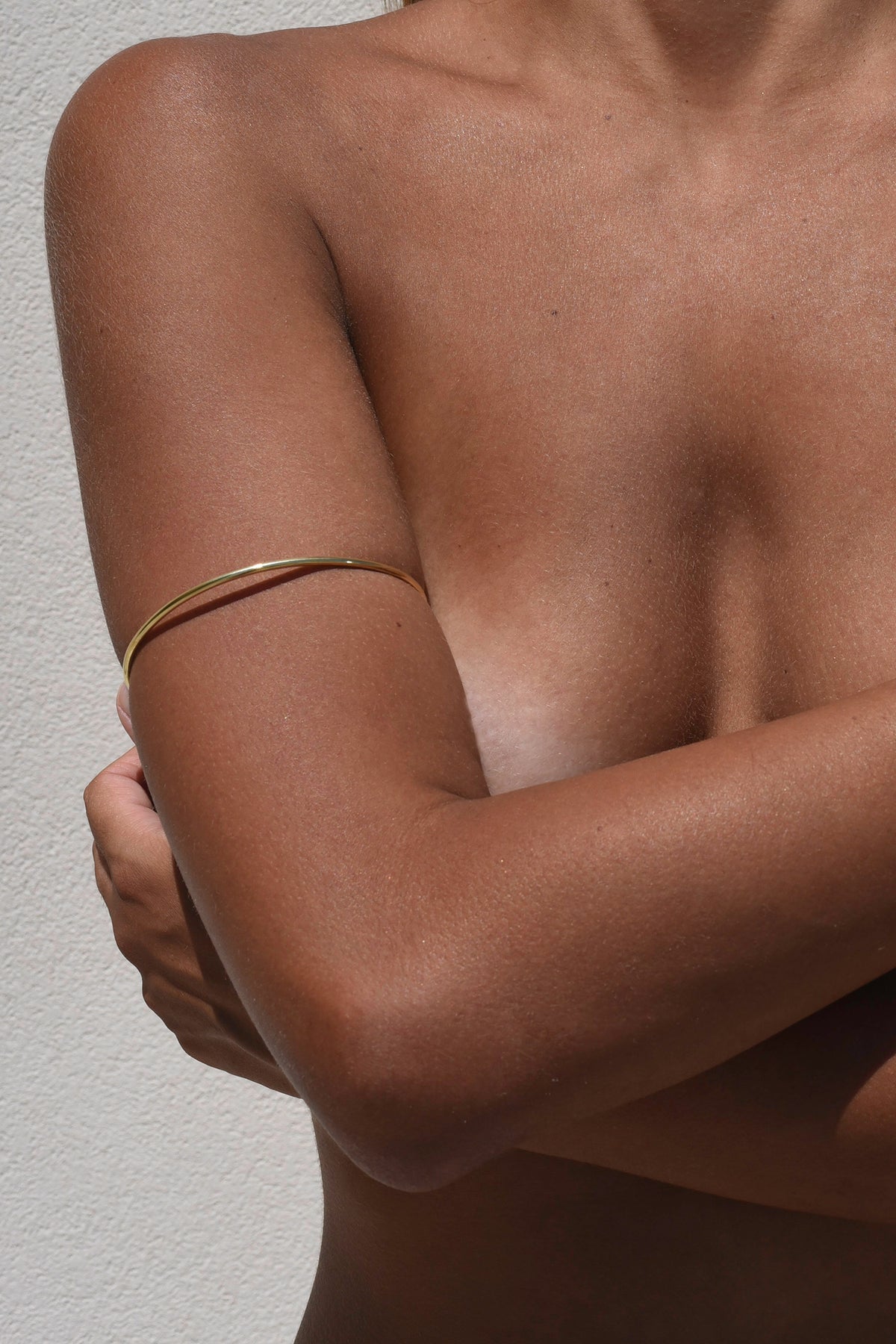 A models upper body showing the gold Delos Arm Cuff on skin, 2,5 mm brass wire.