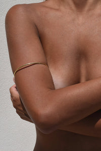 A models upper body showing the gold Delos Arm Cuff on skin, 2,5 mm brass wire.