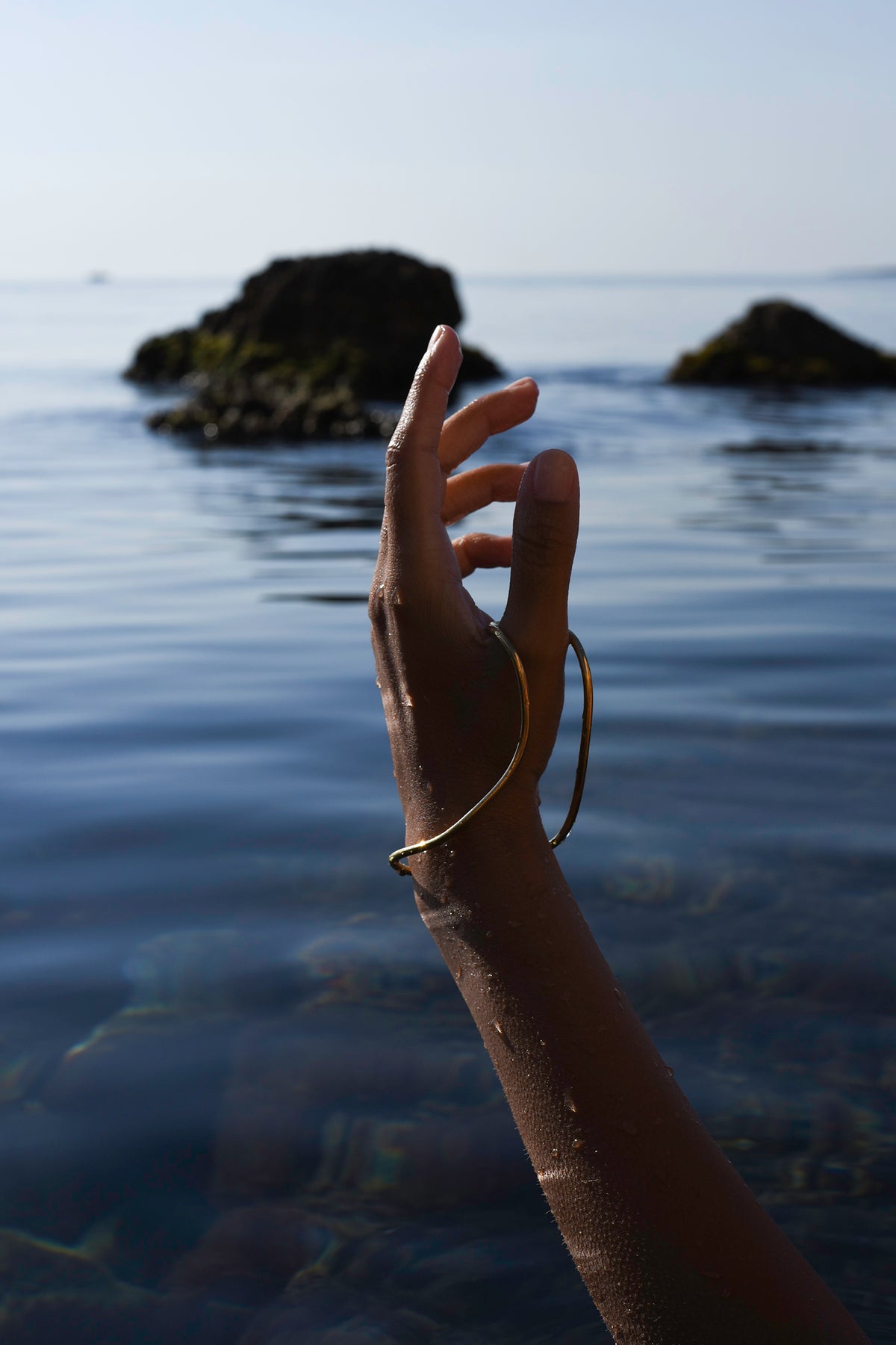 Gold Delos hand bracelet worn against the Mediterranean Sea in Ortigia, Sicily.
