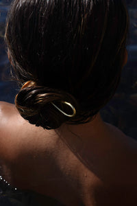 Gold Delos hair pin styled in a wet hair bun, MVDT Collection Ortigia.