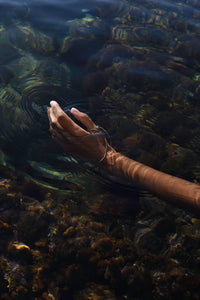 Handcrafted gold Delos thumb bracelet worn in the Mediterranean Sea in Ortigia, Sicily.