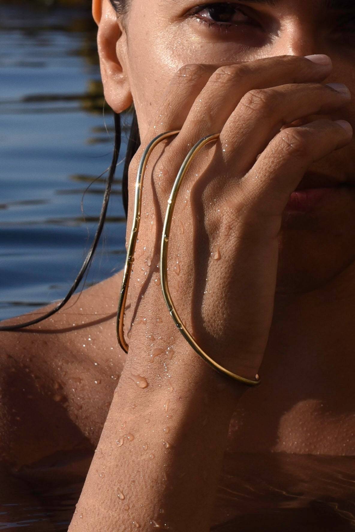 A close-up lifestyle shot of a model in shallow water wearing a handcrafted hand bracelet connected as ring made by MVDT collection.